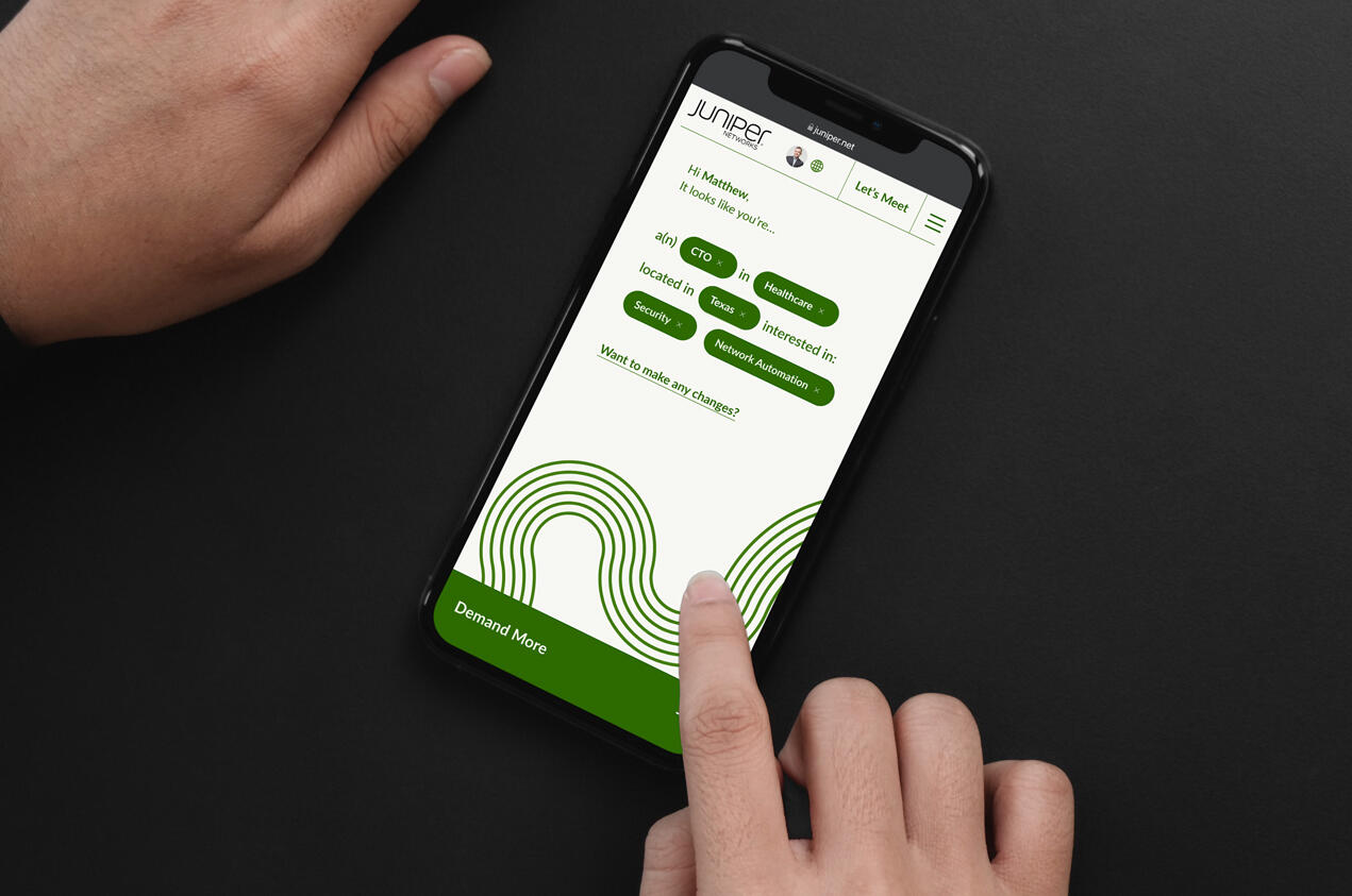 A close up image of a hand holding an iPhone showing the reimagined experience of Juniper's homepage for a new customer.