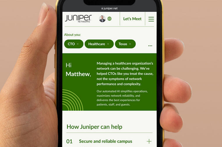 A close up image of a hand holding an iPhone showing the reimagined experience of Juniper's homepage for a new customer.