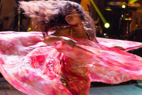 A beautiful dancer wearing a pink bellydance costume twirling.